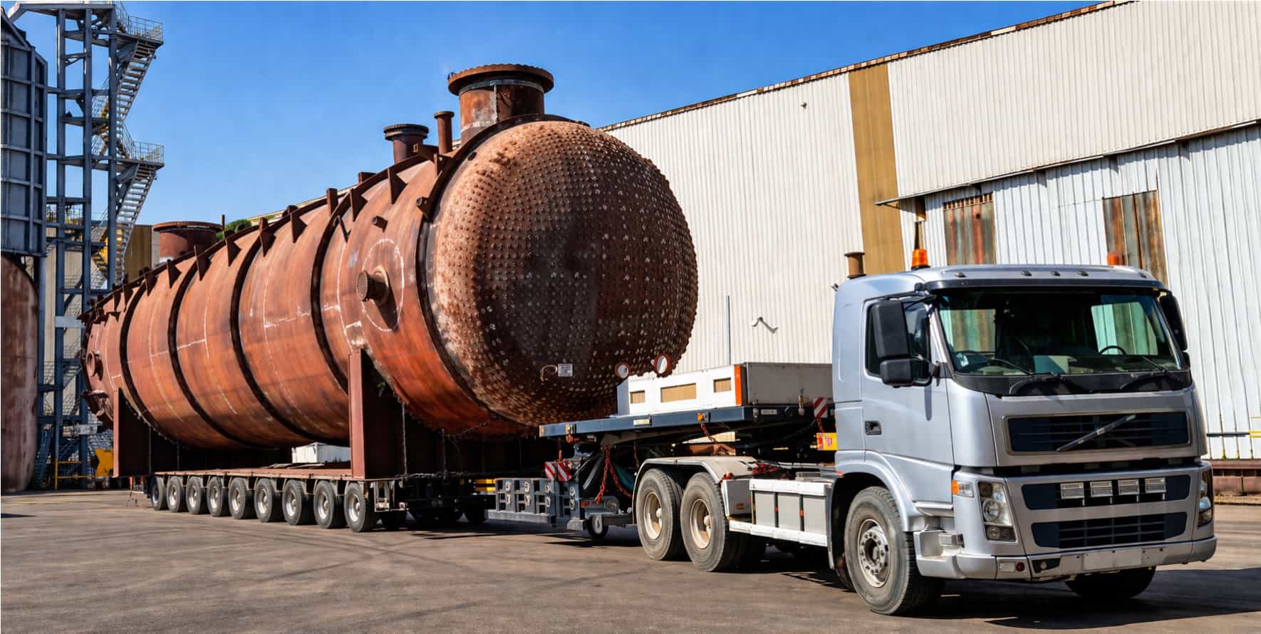 Large rust-coloured spherical pressure vessels on multi-axle trailer