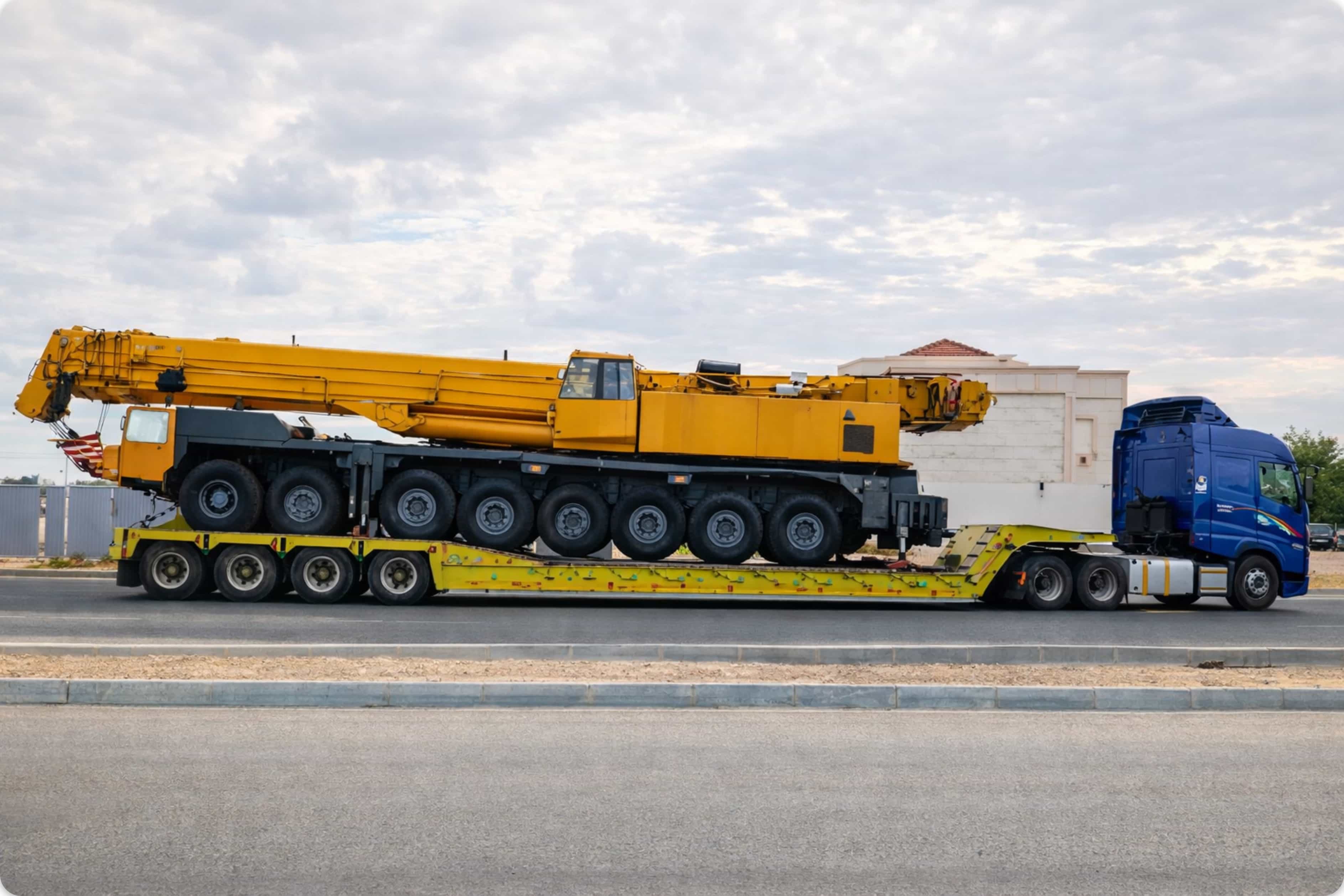 Yellow mobile crane on multi-axle lowbed trailer